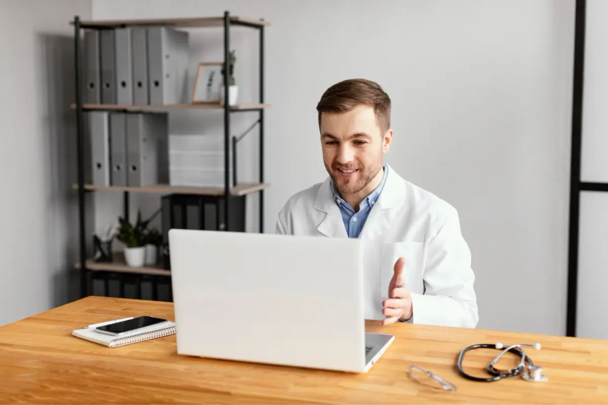 Telehealth doctor in white coat smiling during a video consultation, reflecting digital care at Human Medical Billing