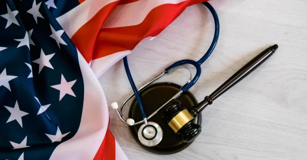 American flag with stethoscope and gavel symbolizing U.S. healthcare laws and insurer downcoding issues.