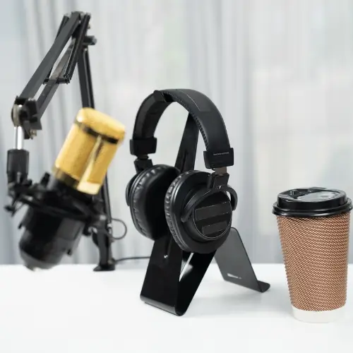 Podcast recording setup with microphone, headphones, and coffee, used for expert interviews in healthcare billing.